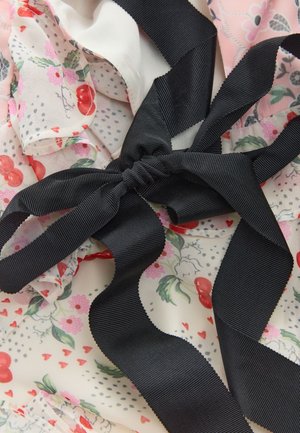 Czarna wstążka grosgrain związana w kokardę na tkaninie w kwiaty z czerwonymi wiśniami, różowymi kwiatami, zielonymi liśćmi i małymi czerwonymi serduszkami.