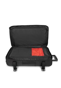 Valigia nera con ruote e zip, dotata di tasca interna rossa. Design rettangolare con lato morbido e texture in tessuto. Aperta, mostrando lo spazio di archiviazione.