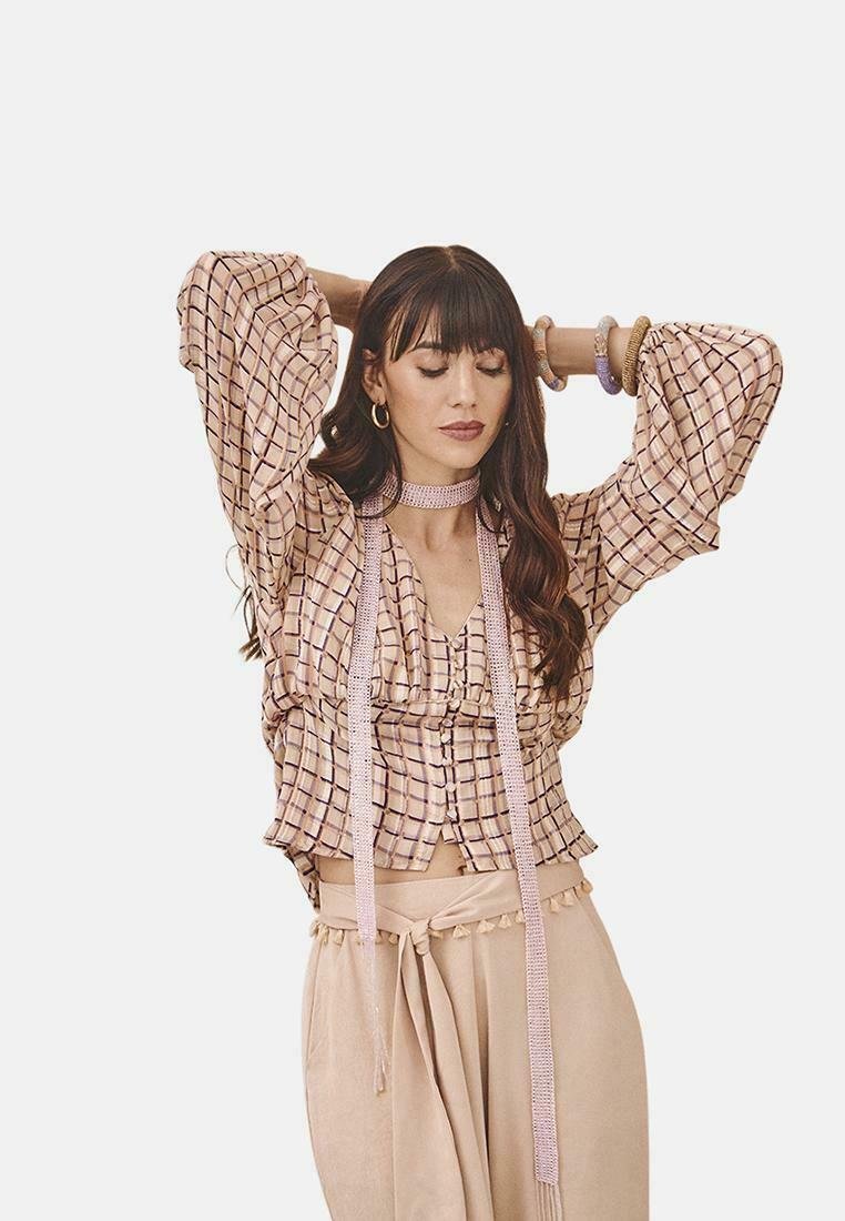 Blusa corta de color rosa claro con un patrón de cuadros, mangas acampanadas, botones frontales y acentos de cinta. Combinada con pantalones de talle alto beige.