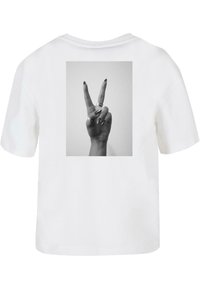 Weißes Baumwoll-T-Shirt mit einem schwarz-weißen Grafikdesign von einer Hand, die ein Friedenszeichen macht, mit Ringen an den Fingern. Lockere Passform, kurze Ärmel.