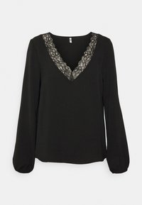Blouse noire à manches longues avec col en V orné de dentelle et poignets légèrement froncés sur les manches.