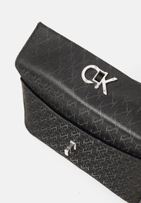 Borsa a tracolla nera con motivo, caratterizzata da un'esterno in tessuto testurizzato, hardware in argento e un logo prominente in rilievo sulla patta.