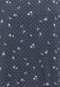 Dark blue fabric with small white polka dots and a floral pattern in light blue. Material appears soft, with a smooth texture.