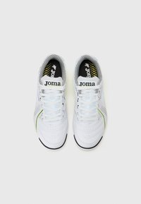Białe buty do piłki nożnej z siateczkowym wykończeniem, zielonymi akcentami i czarną podeszwą. Posiadają sznurowaną konstrukcję oraz logo "Joma" na języku.