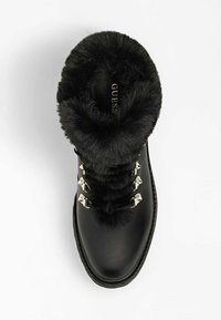 Svart läder ankelboot med fuskpälskrage och silverfärgade snörhakar, sett ovanifrån.