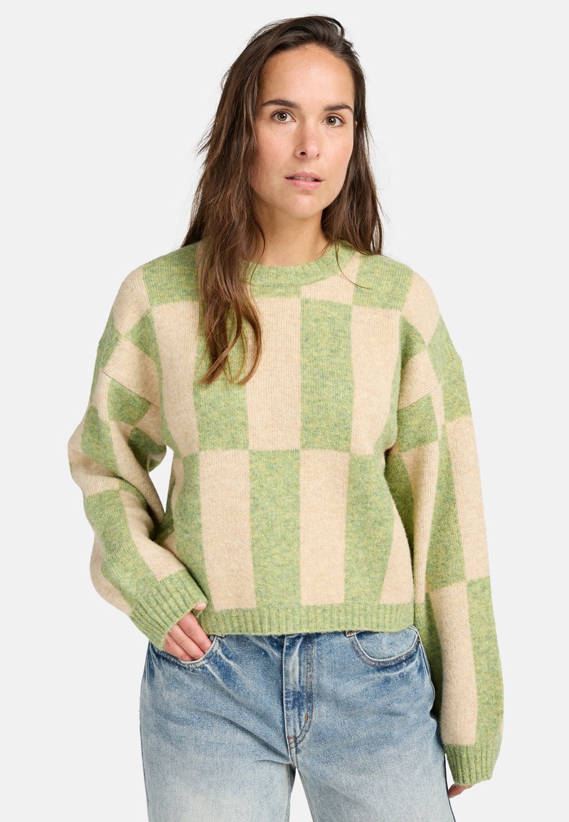 Groen en crèmekleurig geblokt trui, met een relaxte pasvorm, ronde halslijn, geribbelde manchetten en een zachte textuur. Gecombineerd met lichtblauwe denim jeans.