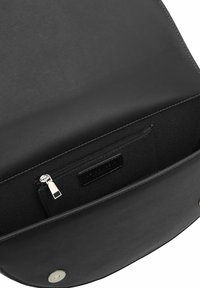 Interno di borsa in pelle nera con una texture liscia, dotata di una tasca con zip e un'etichetta. Chiusura a pressione tonda in metallo visibile.