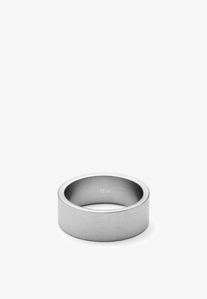 Anillo de banda ancha de metal plateado con acabado cepillado y grabado "DW" en la superficie interior, mostrado contra un fondo blanco.