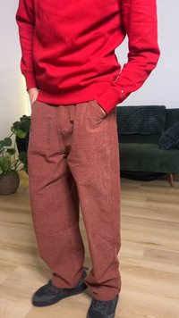 Checker-patterned, loose-fitting red pants with elastic waistband; worn with a red sweater and black shoes. Texture appears soft and comfortable.