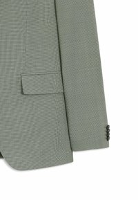 Manche et devant de blazer vert clair texturé avec poche à rabat et quatre boutons foncés sur le poignet, présenté sur fond blanc.
