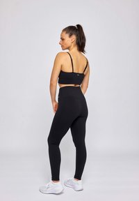 Soutien-gorge de sport noir et legging taille haute, tous deux avec une texture côtelée. Les leggings présentent un design sans coutures avec un accent logo à l'arrière.