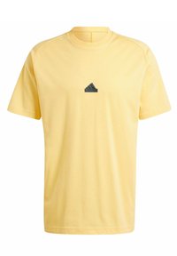 Żółta koszulka z krótkim rękawem wykonana z bawełny, z okrągłym dekoltem. Posiada czarne logo adidas na piersi. Miękka struktura i luźny krój.