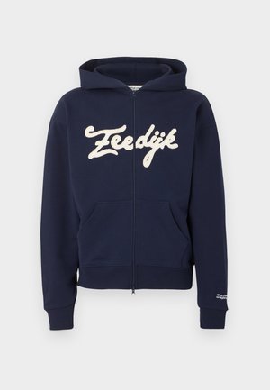 Temno modra kapucar s sprednjimi žepi, rebrastimi manšetami in spodnjim robom, kremn tekst "Zeedijk" čez prsi ter majhen bel napis na manšeti levega rokava.