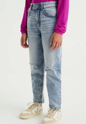 Ljusblå högmidjade mom-jeans med slitna knän, kombinerade med beige och vita sneakers. Modell bär en strukturerad rosa topp.