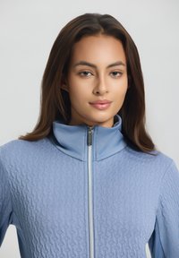 Helles blaues Zip-Jacke mit hohem Kragen, ausgestattet mit einem strukturierten Muster und einem glatten Futter am Kragen sowie Reißverschlussdetails.