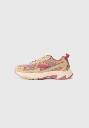 Beige og pink mesh sneakers med en chunky sål, accentueret af lilla elementer og en rød trækflap ved hælen. Teksturerede overfladedetaljer synlige.