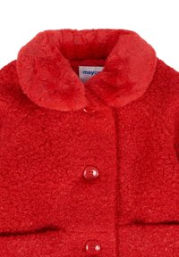 Cappotto rosso con texture, colletto in peluche e grandi bottoni abbinati, che mostra il dettaglio della parte alta davanti e un'etichetta del marchio all'interno del colletto.