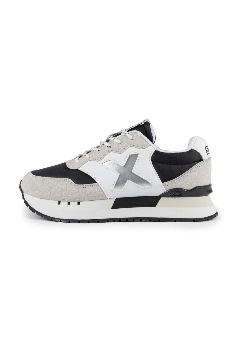 Zapatillas deportivas con un esquema de colores en negro, blanco y gris. Hechas de ante y material sintético, con una suela texturizada y un logo distintivo.