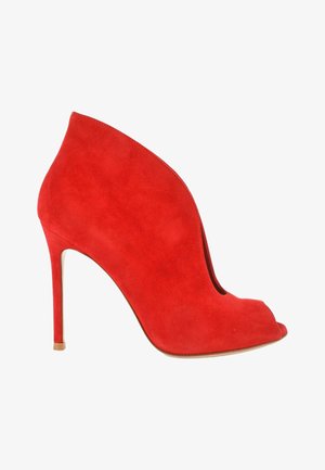 Bottine à talon haut en daim rouge avec un design à bout ouvert et un talon stiletto fin sur fond blanc.