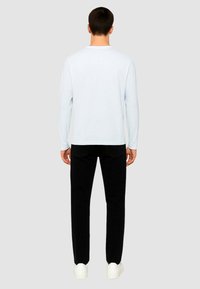 Camicia a maniche lunghe azzurro chiaro e pantaloni neri, abbinati a sneaker bianche. Tessuto morbido, design semplice e vestibilità standard.