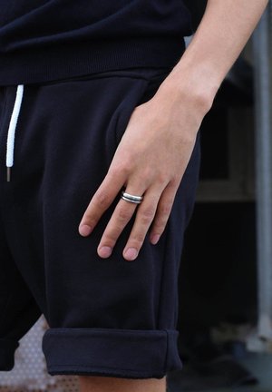 Black cotton lounge shorts with white drawstring, featuring a hand resting on the pocket. A silver and chrome ring adorns the finger.