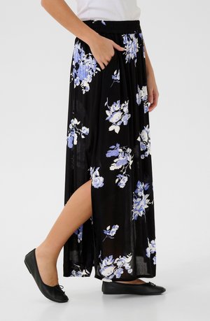 Sort blomster maxi nederdel med blå og hvide blomster mønstre, elastisk talje og sidelommer. Båret med sorte flade sko.