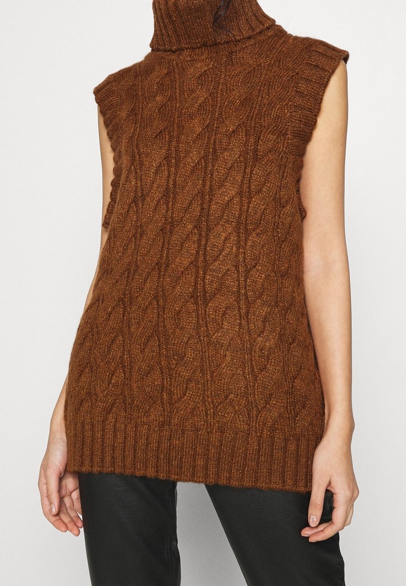 Hnědý pletený svetřík bez rukávů s vysokým límcem, zdobený copánkovým vzorem a žebrovaným lemem. Vyrobený z texturované příze.