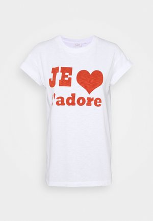 Biała koszulka z krótkim rękawem z podwiniętymi rękawami i czerwonym napisem "JE" po którym następuje symbol serca oraz "d'adore" na przodzie.
