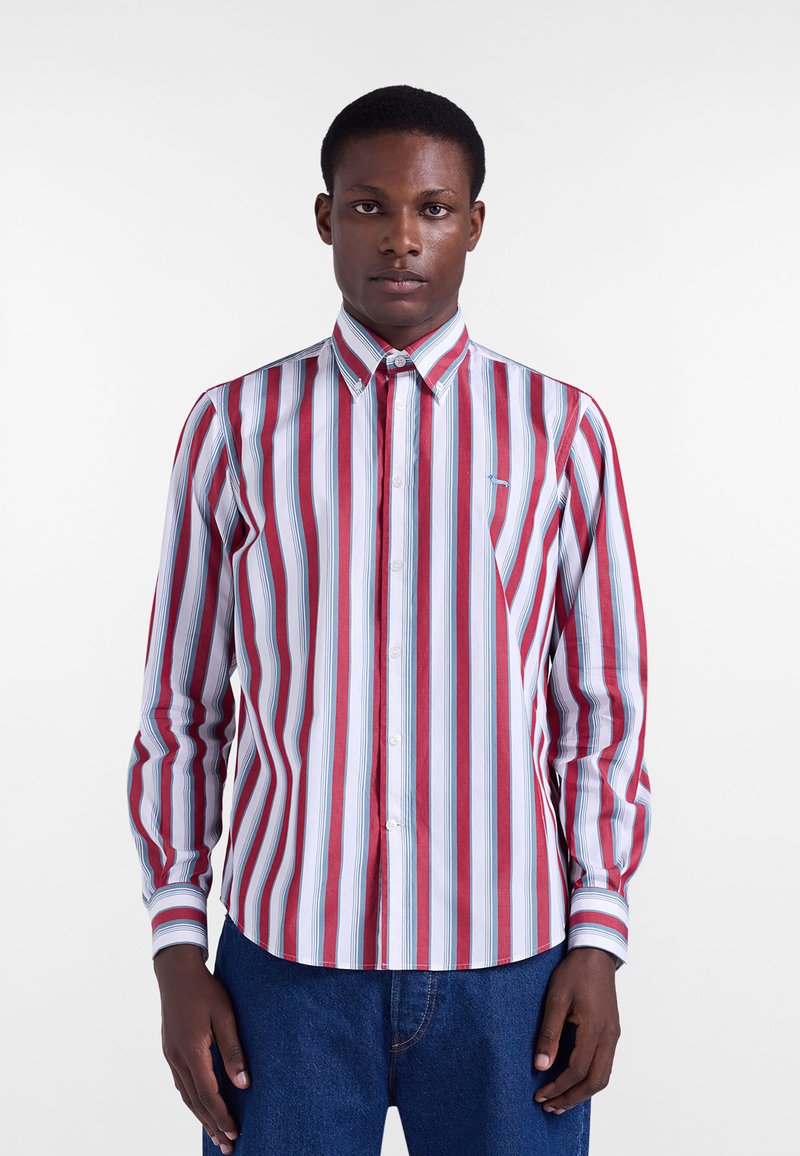 Chemise à rayures boutonnée avec des rayures verticales rouges, blanches et bleues, manches longues et col classique. Présente un petit logo sur la poitrine.
