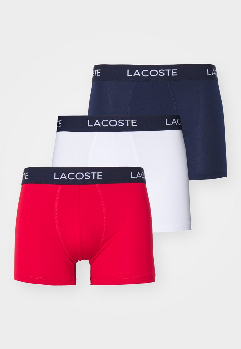 Három darab boxer alsónemű piros, fehér és sötétkék színben, elasztikus pántokkal, amelyeken a "LACOSTE" logó található. Puha, rugalmas anyagból készült.