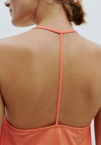 Rückenpartie mit Trägerdesign aus sanftem Korallestoff, glatte Textur, minimalistischer Stil, der die Haut präsentiert und eine saubere, einfache Silhouette zeigt.
