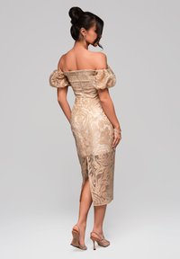 Off-shoulder, beige klänning med puffärmar, blommönster, knälängd med sidoklyfta, parat med remsandaler på hög klack.