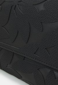 Schwarze, strukturierte Leder-Clutch mit geprägt floralem Muster, featuring genähten Kanten und einer glatten Oberfläche. Kompaktes und elegantes Design.