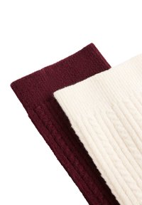 Burgunderfarvede og cremefarvede strikkede stofstykker med teksturerede mønstre. Burgunder har ribstrikdetaljer; creme har kabelstrikdesign.