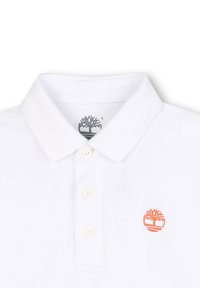 Witte polo met een textuurstof, voorzien van een grijs logo op de kraag en een klein oranje boomemblem op de borst. Vier knopen placket.
