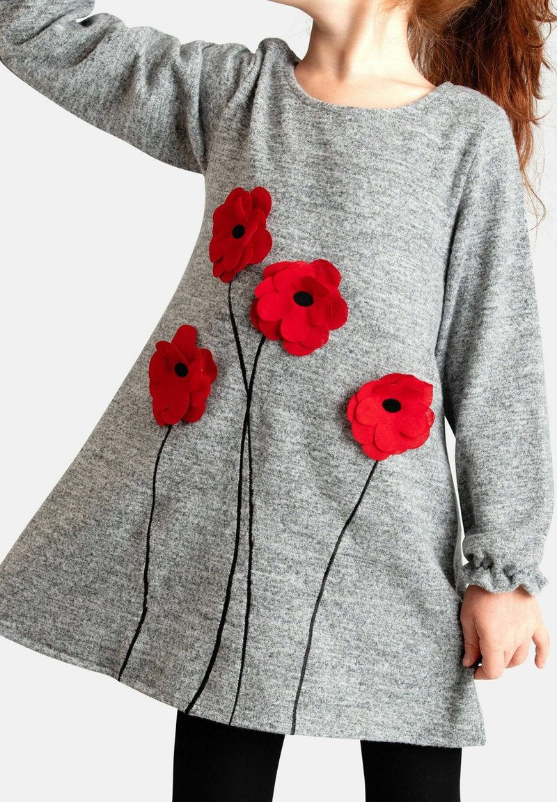 Enfant portant une robe grise à manches longues avec quatre fleurs de pavot rouges et des tiges noires à l'avant sur un fond blanc.