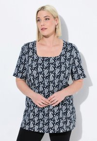 Túnica de manga corta azul marino con escote cuadrado, presenta un patrón de paisley blanco y un corte relajado. Textura suave, llega a la cadera.