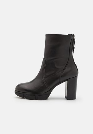 Black leather ankle boot with a square toe, side zipper, and a chunky heel. Features subtle stitching detail and rubber sole for traction.