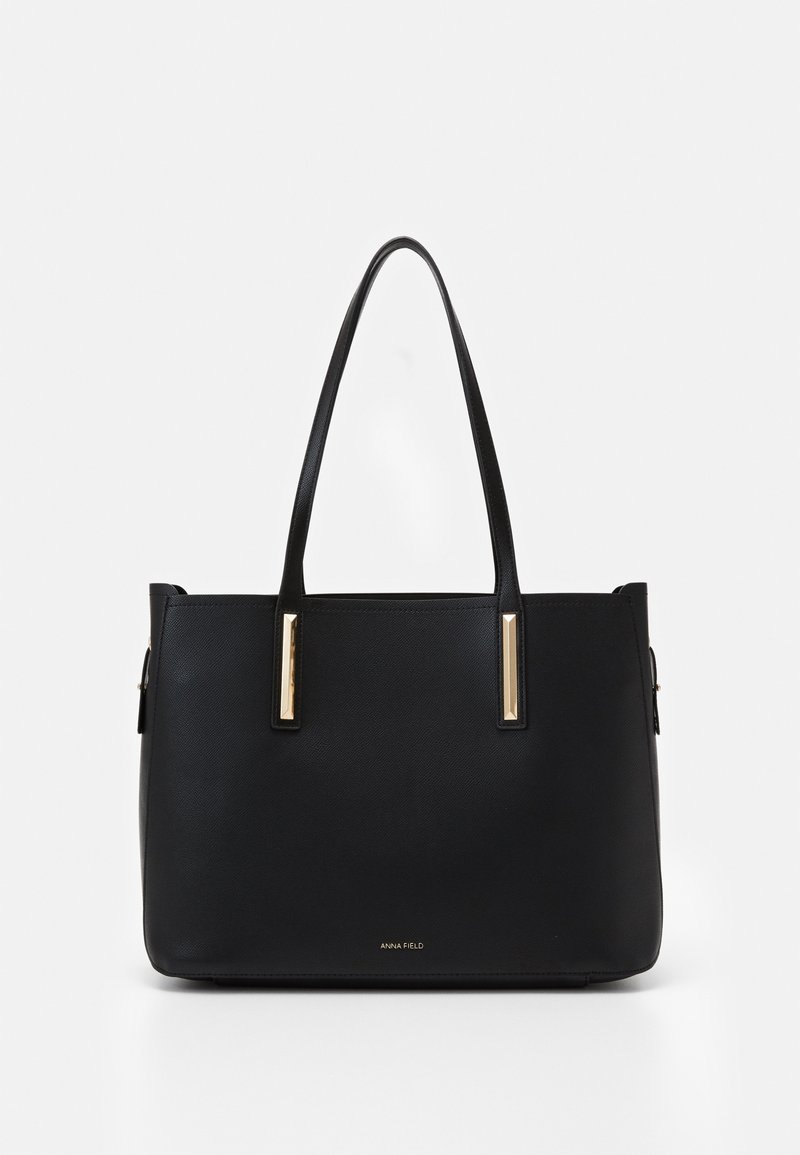 Sac à main structuré noir avec deux longues anses, des accents rectangulaires dorés et le logo « Anna Field » au centre devant.