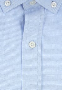 Camicia azzurra chiaro con bottoni a pressione, caratterizzata da un motivo testurizzato, con bottoni bianchi e cuciture curate lungo la pattina e il colletto.