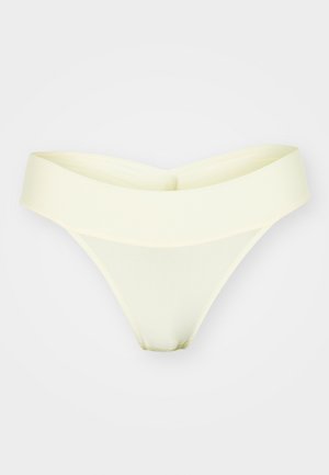 Šviesiai geltonos thong tipo apatinės kelnaitės su plačia, minkšta talija ir lygiu, elastingu audiniu. Nėra matomų siūlių ar raštų.