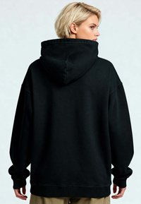 Felpa nera oversize con un ampio cappuccio, polsini e orlo a costine, realizzata in materiale morbido, con una superficie liscia e una vestibilità comoda.