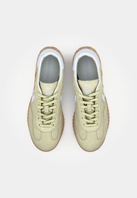 Adidași din piele întoarsă verde deschis cu partea superioară texturată, vârf rotund și talpă din cauciuc bej. Prezintă accente albe și șireturi plate.