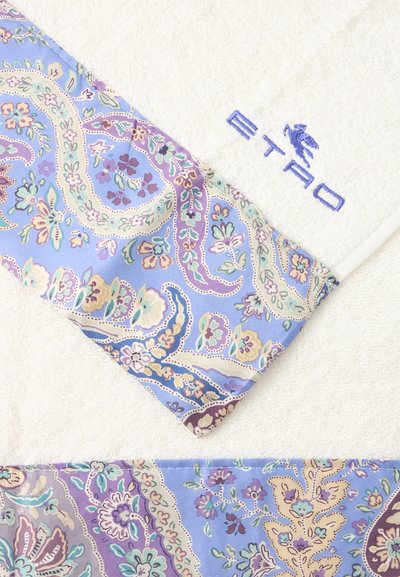 Serviette blanche avec logo "ETRO" brodé en bleu et une bordure en tissu à motif fleuri cachemire bleu, violet et crème.