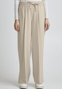 Beige, széles lábú nadrág, elasztikus derékpánttal és húzózsinórral, sima, könnyű anyagból készült, laza fazonnal.