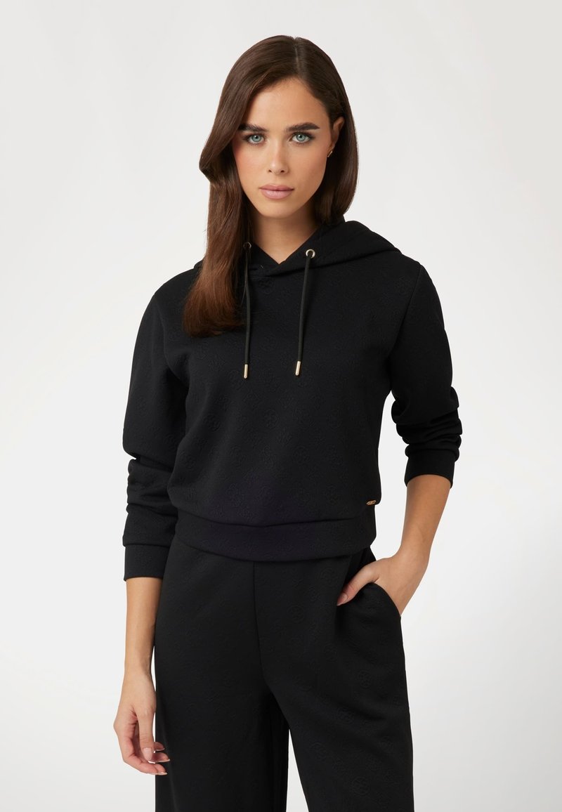 Felpa nera con un leggero motivo testurizzato, coulisse regolabile con punte dorate, polsini e orlo a costine, abbinata a pantaloni neri coordinati.