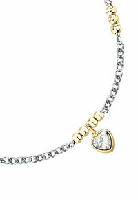 Bracciale in argento con accenti di palline dorate e un ciondolo a forma di cuore con una pietra trasparente in montatura dorata.