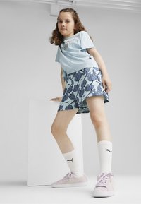 Camiseta de manga corta azul claro, pantalones cortos azules con un diseño floral, calcetines deportivos blancos y zapatillas rosas con detalles blancos.