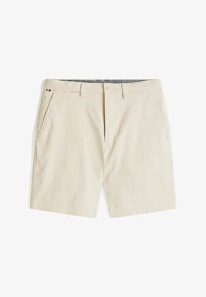 Bežiniai medvilniniai šortai su lygia priekiu, šoninėmis kišenėmis ir maža trikampio spalvų akcentine etikete ant juosmens. Yra diržo kilpos.