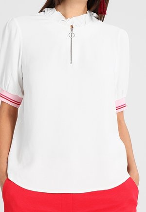 Blusa blanca de manga corta con cuello con volantes, cremallera frontal y detalles de rayas rosas en las mangas. Tejido suave con un ajuste relajado.